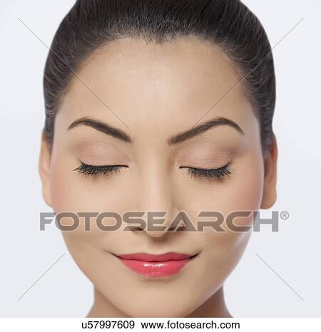 Stock Photo - An attractive young woman with eyes closed smiling over white background . Fotosearch