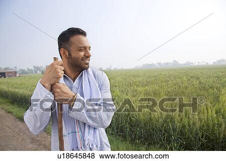 Stock Photo - An Indian man looking away while holding a stick . Fotosearch