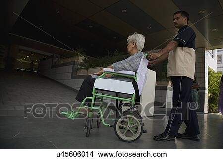 Attendant helping patient on wheelchair View Large Photo Image Picture - Attendant helping patient on wheelchair . Fotosearch