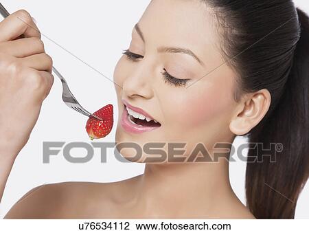 Stock Image - Attractive female eating strawberry . Fotosearch