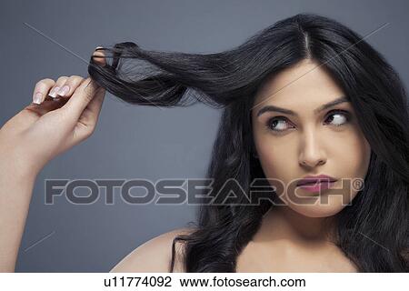 Attractive young woman twisting hair around her finger over colored background View Large Photo Image Stock Image - Attractive young woman twisting hair around her finger over colored background . Fotosearch