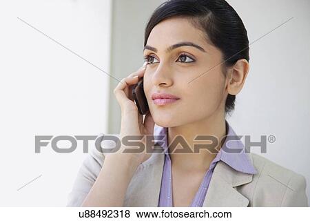 Beautiful businesswoman smiling while using mobile phone in office View Large Photo Image Stock Photo - Beautiful businesswoman smiling while using mobile phone in office . Fotosearch