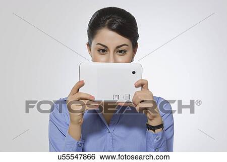 Stock Photograph - Beautiful businesswoman using digital tablet against gray background. Fotosearch