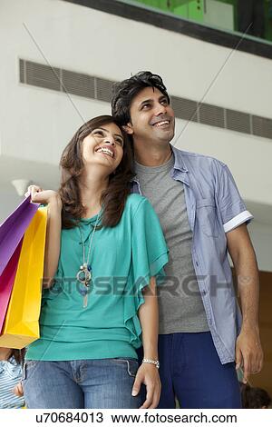 Stock Image - Beautiful couple in shopping mall looking away . Fotosearch