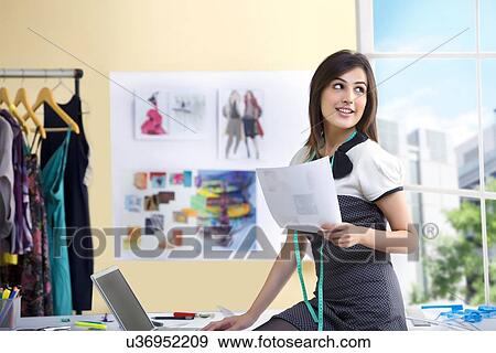 Stock Photo - Beautiful young designer using laptop in studio . Fotosearch