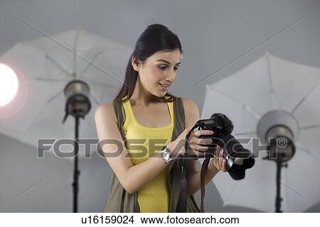 Beautiful young female photographer looking into digital camera View Large Photo Image Picture - Beautiful young female photographer looking into digital camera . Fotosearch