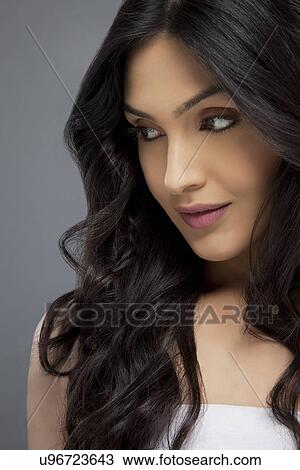 Beautiful young female with long hair looking away over colored background View Large Photo Image Stock Image - Beautiful young female with long hair looking away over colored background . Fotosearch
