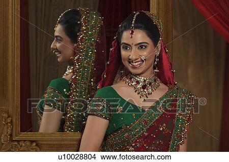 Picture - Beautiful young Indian bride standing in front of mirror . Fotosearch