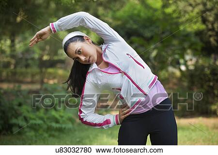 Stock Image - Beautiful young lady stretching in park . Fotosearch