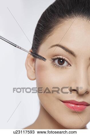 Stock Image - Beautiful young woman applying mascara . Fotosearch