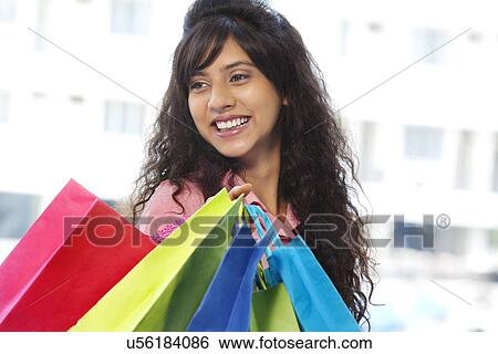 Stock Photograph - Beautiful young woman carrying shopping bags . Fotosearch