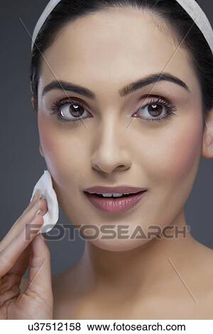 Beautiful young woman cleansing her face over colored background View Large Photo Image Stock Photo - Beautiful young woman cleansing her face over colored background . Fotosearch