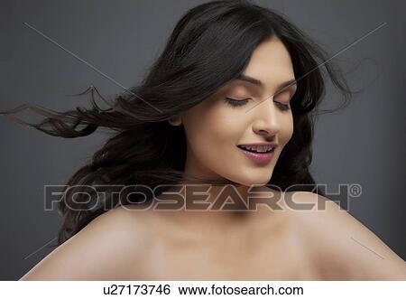 Beautiful young woman enjoying the breeze over colored background View Large Photo Image Stock Photograph - Beautiful young woman enjoying the breeze over colored background . Fotosearch