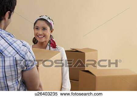 Stock Photography - Beautiful young woman holding cardboard box with man . Fotosearch