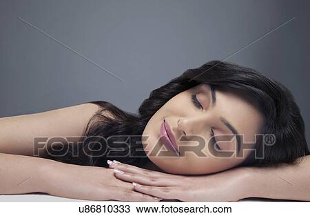 Stock Image - Beautiful young woman sleeping on her hands over colored background . Fotosearch