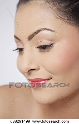 Stock Photo - Beautiful young woman smiling and looking down . Fotosearch