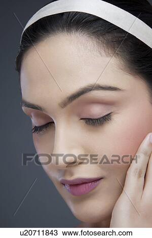 Stock Image - Beautiful young woman touching her face over colored background . Fotosearch