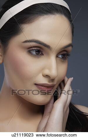 Beautiful young woman touching her face over colored background View Large Photo Image Stock Image - Beautiful young woman touching her face over colored background . Fotosearch