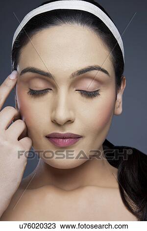 Stock Image - Beautiful young woman with eyes closed over colored background . Fotosearch