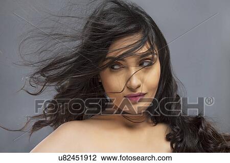 Beautiful young woman with hair blowing over face against colored background View Large Photo Image Stock Image - Beautiful young woman with hair blowing over face against colored background . Fotosearch