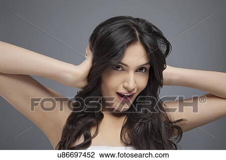 Stock Image - Beautiful young woman with her hands covering her ears over colored background . Fotosearch