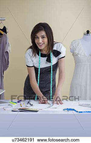 Stock Image - Beautiful young woman working in fashion studio . Fotosearch