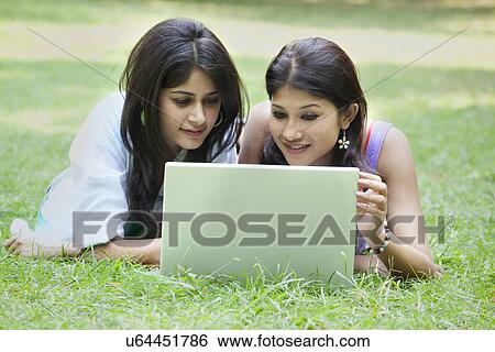 Beautiful young women lying on grass and using laptop View Large Photo Image Stock Photograph - Beautiful young women lying on grass and using laptop . Fotosearch