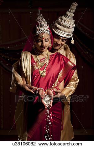 Stock Image - Bengali bride and groom making an offering . Fotosearch