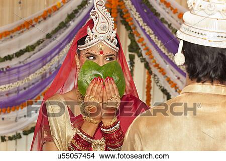 Picture - Bengali bride hiding her face from the groom . Fotosearch