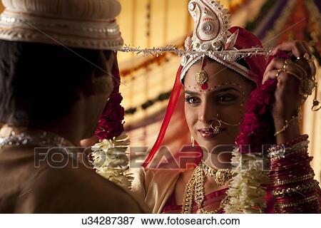 Stock Photo - Bengali bride putting a garland on groom . Fotosearch