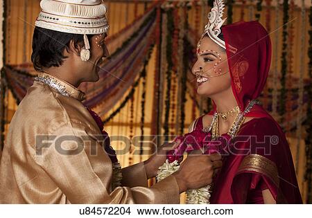 Bengali groom putting a garland on a bride View Large Photo Image Picture - Bengali groom putting a garland on a bride . Fotosearch