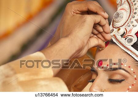 Picture - Bengali groom putting sindoor on brides forehead . Fotosearch