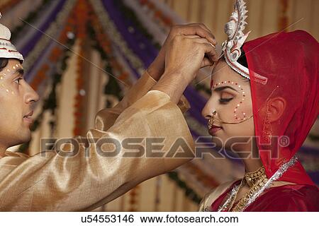 Bengali groom putting sindoor on brides forehead View Large Photo Image Stock Photograph - Bengali groom putting sindoor on brides forehead . Fotosearch