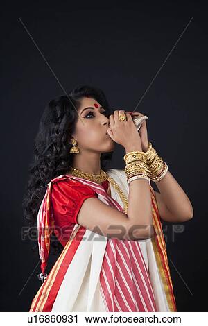 Bengali woman blowing on a conch shell View Large Photo Image Stock Image - Bengali woman blowing on a conch shell. Fotosearch