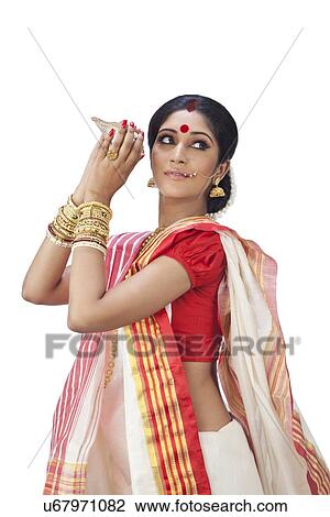 Stock Image - Bengali woman holding a conch shell. Fotosearch