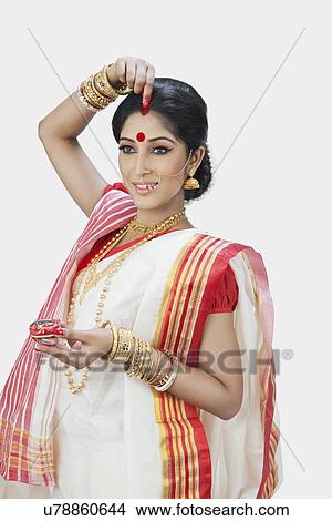 Bengali woman putting sindoor on her forehead View Large Photo Image Picture - Bengali woman putting sindoor on her forehead. Fotosearch