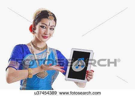 Stock Photo - Bharatanatyam dancer showing music note and CD on digital tablet over white background. Fotosearch