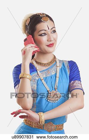 Stock Image - Bharatanatyam dancer using smart phone over white background. Fotosearch