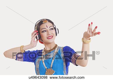 Bharatanatyam dancer wearing headphones while dancing over white background View Large Photo Image Stock Photo - Bharatanatyam dancer wearing headphones while dancing over white background. Fotosearch