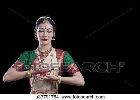 Picture - Bharatanatyam dancer with eyes closed performing over black background. Fotosearch