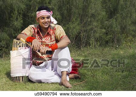 Picture - Bihu dancer sitting with a dhol . Fotosearch