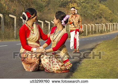 Stock Image - Bihu dancers squatting as Bihu man walks up . Fotosearch