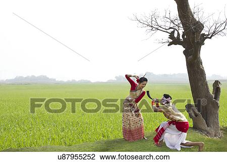 Stock Image - Bihu man blowing on a pepa while Bihu woman dances to his tune . Fotosearch