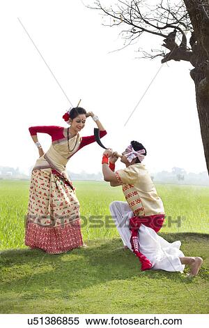 Stock Photography - Bihu man blowing on a pepa while Bihu woman looks on . Fotosearch