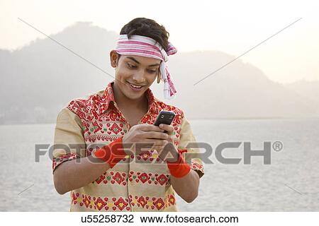 Stock Image - Bihu man reading an sms on a mobile phone . Fotosearch