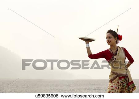 Stock Photograph - Bihu woman dancing with a brass plate . Fotosearch
