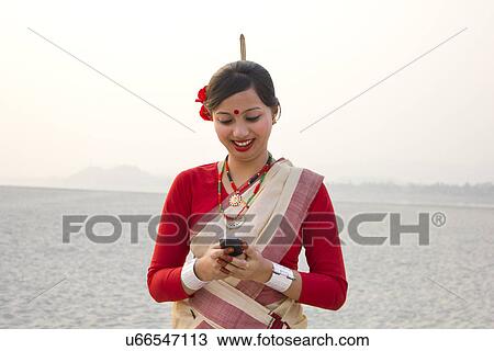 Stock Image - Bihu woman reading an sms on a mobile phone . Fotosearch