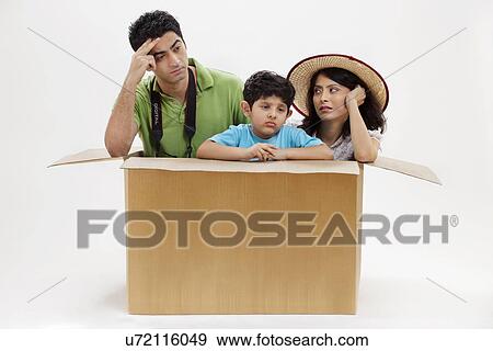 Stock Photo - Bored young couple sitting inside cardboard box with little son . Fotosearch