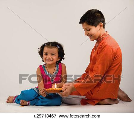 Boy and girl holding a diya together View Large Photo Image Stock Photo - Boy and girl holding a diya together . Fotosearch