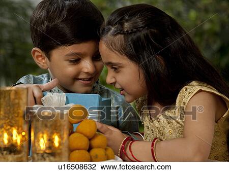 Stock Image - Boy and girl opening gifts on Diwali . Fotosearch